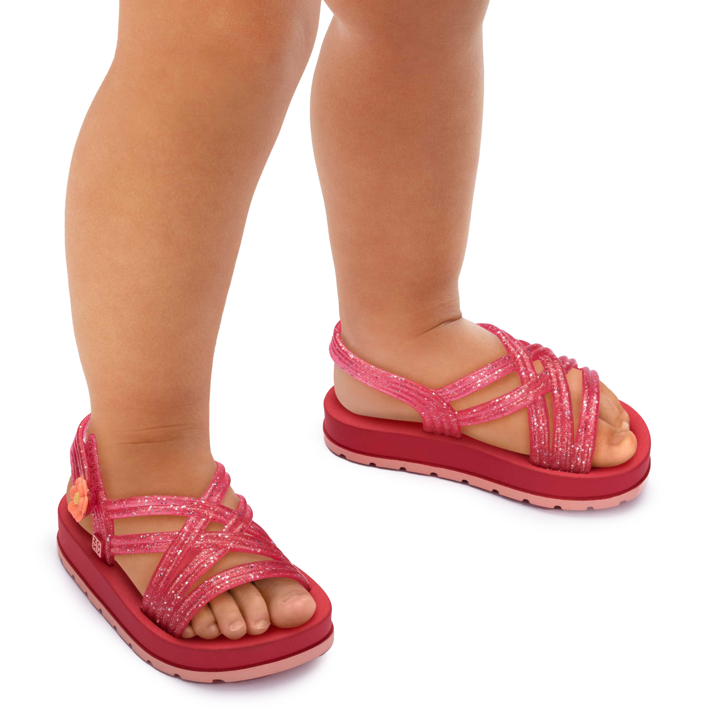 Sandália infantil rosa-escuro com tiras translúcidas glitter e flor laranja no calcanhar, vista frontal com fundo branco